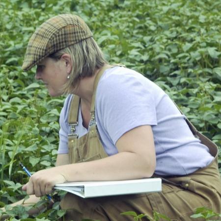 A woman in a field with a notebook