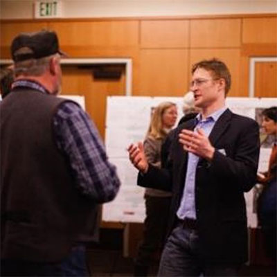 Two men talking at a poster session open house.